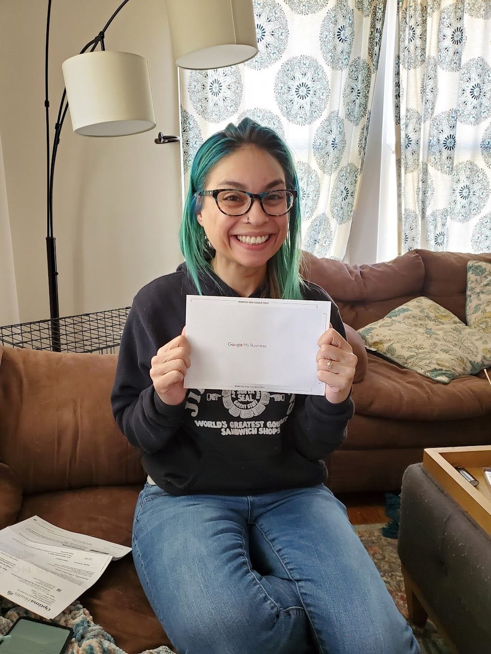Joa holds her Google My Business card, making Prism Consulting official.